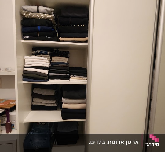 בגדים מקופלים בארון עם מדפים פתוחים